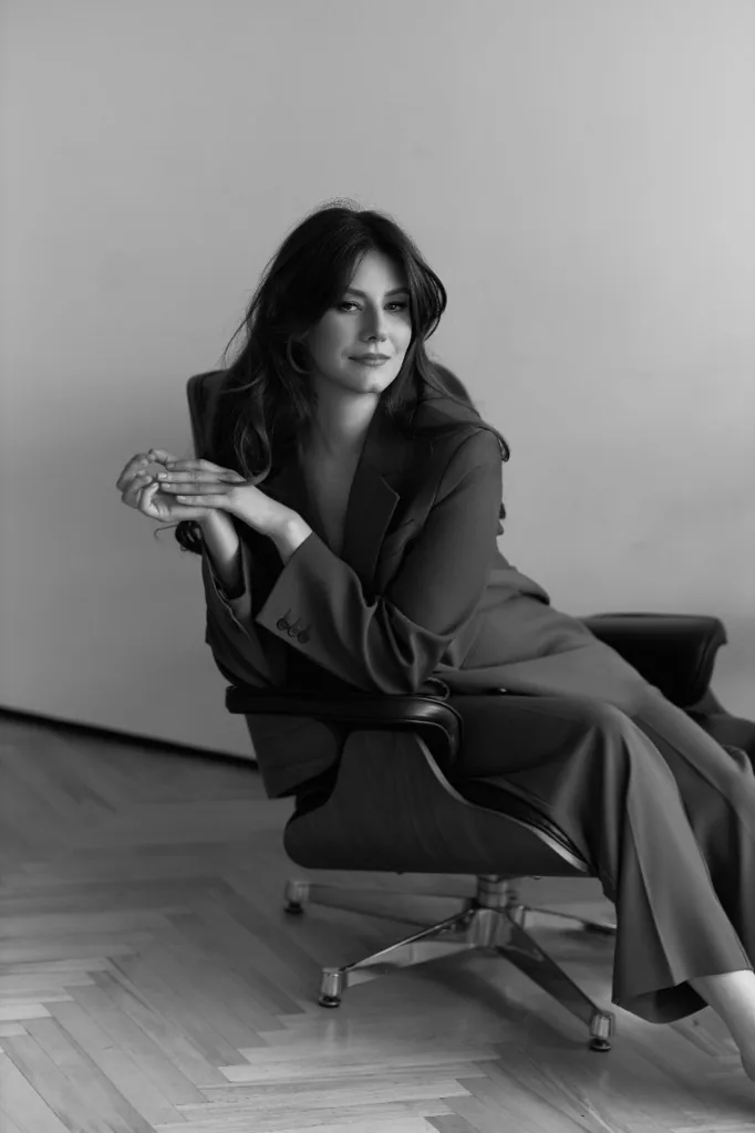 Anastasia Donică, psihonumerolog, portret alb-negru: așezată într-un fotoliu, îmbrăcată într-un costum elegant, privind spre cameră.