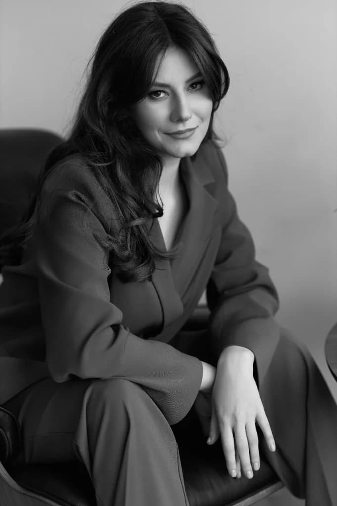 Anastasia Donică, portret vertical alb-negru: așezată pe un scaun, costum elegant, privire directă spre cameră.
