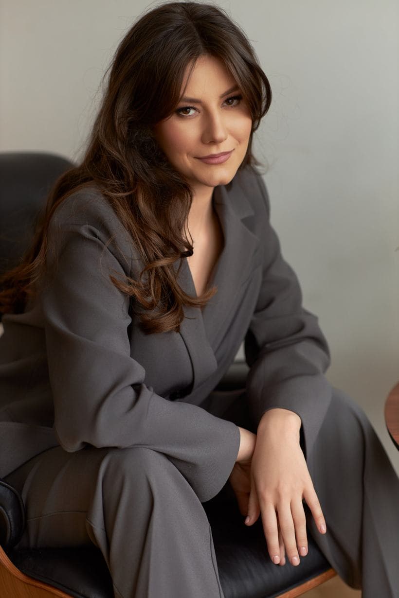 Anastasia Donică, psihonumerolog, în costum gri, așezată într-un fotoliu